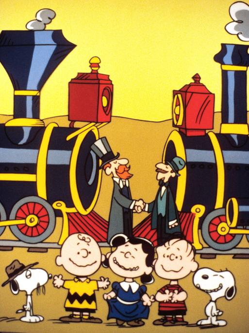 Ein Szenenfoto aus der Zeichentrickserie "The Building of the Transcontinental Railroad" mit den "Peanuts". Im Vordergrund des Bildes sind die "Peanuts"-Figuren Charlie Brown, Lucy und Linus sowie der Hund Snoopy zu sehen. 