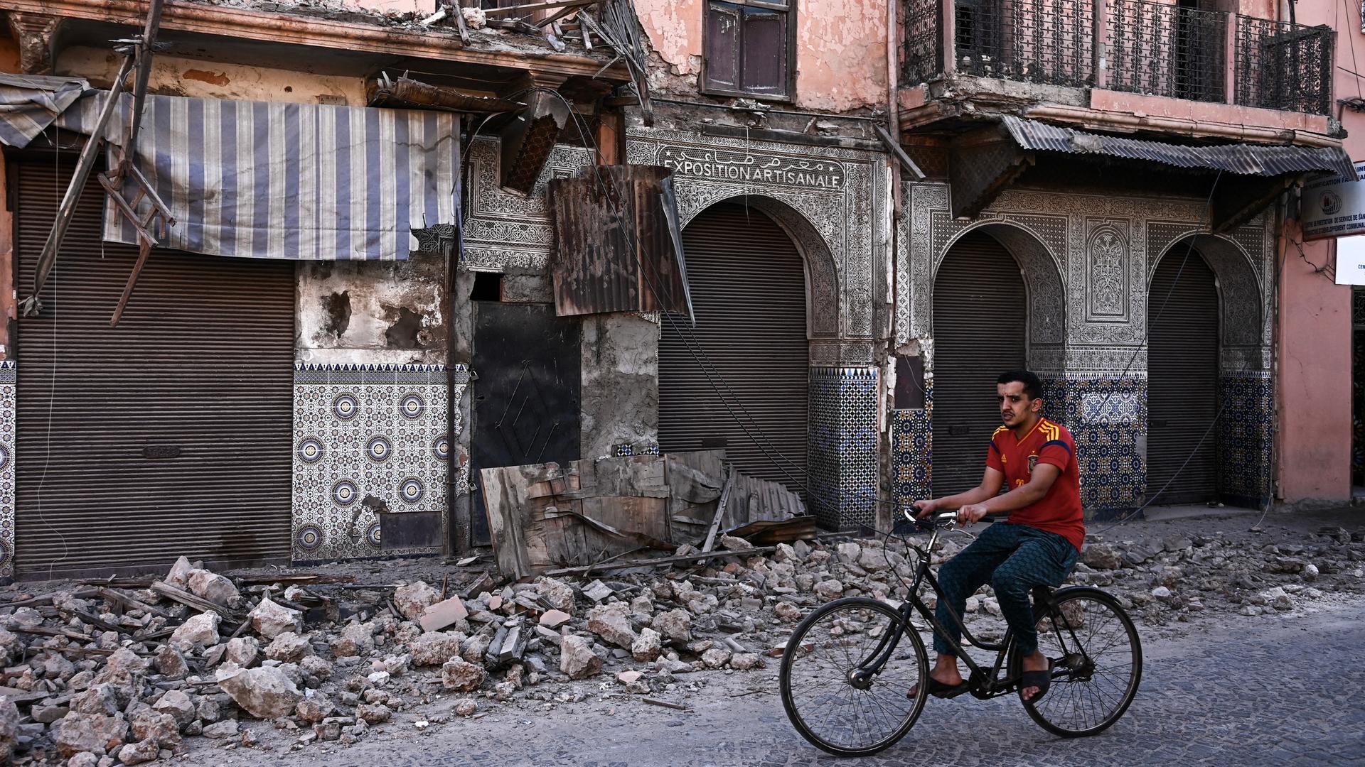 Ein Mann fährt in Marrakesch vorbei an Gebäuden, die durch das Erdbeben in Marrokko beschädigt wurden.