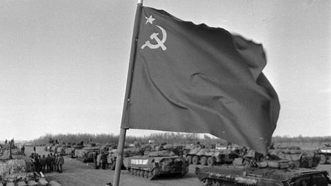 Sowjetische Truppen verlassen 1989 Afghanistan. Über einem Panzer weht die sowjetische Flagge. 