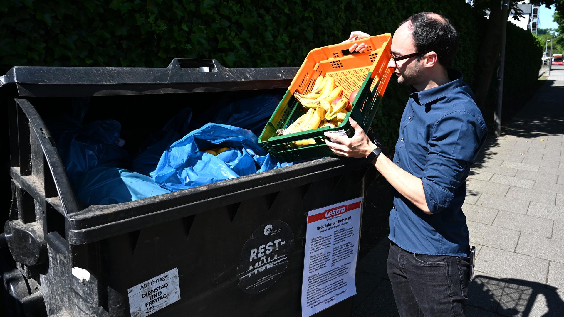Michael Shaw, Mitarbeiter des Supermarktes Lestra, bringt Obst zu einem Container. Das sogenannte "Containern" ist hier erlaubt. An den Müllcontainern wird sogar mit einem Schild darauf hingewiesen, was voraussichtlich noch bedenkenlos gegessen werden kann und wovon man lieber die Finger lassen sollte.
