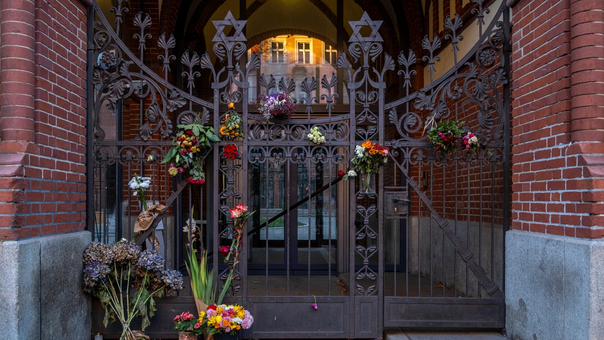 Ein Tor mit Davidsternen, es wird von Kerzen und Blumen geschmückt.