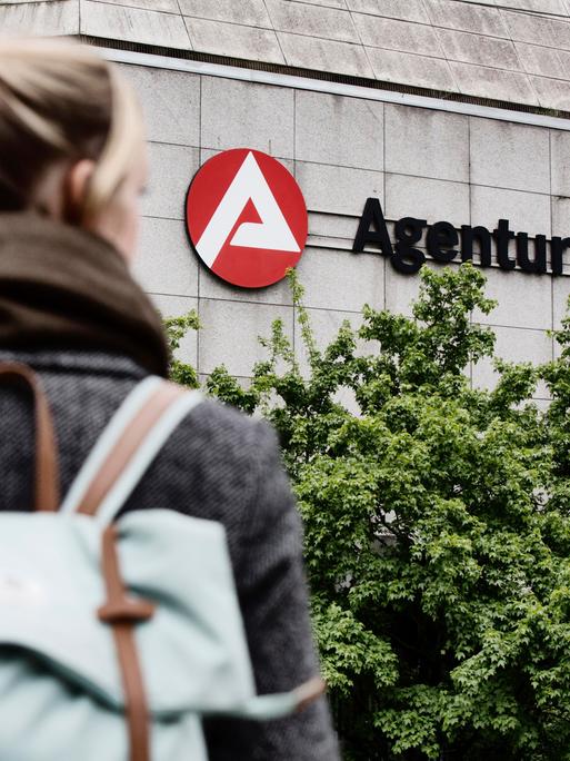 Junge Frau von hinten fotografiert auf dem Weg zur Agentur für Arbeit