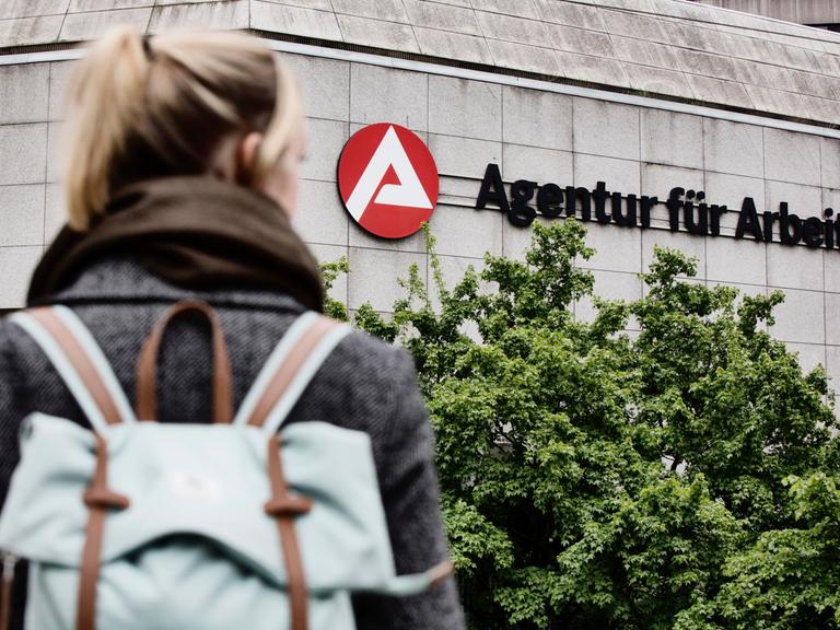 Junge Frau von hinten fotografiert auf dem Weg zur Agentur für Arbeit