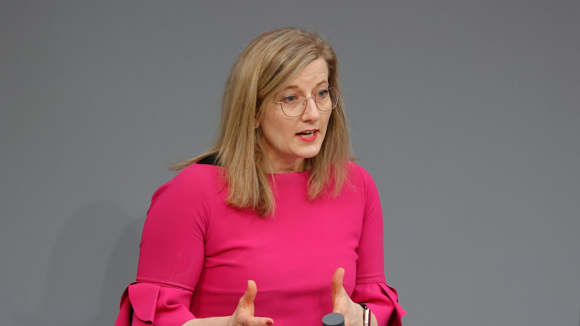 Kristine Lütke FDP steht in einem pinken Kostüm am Rednerpult im Bundestag.  