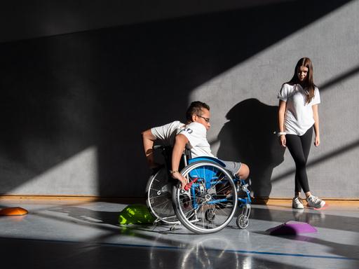 Ein Schüler der Förderschule Paul-Klee-Schule in Celle fährt mit seinem Rollstuhl in der Sporthalle des Gymnasium Burgdorf Slalom um Hindernisse, während eine Schülerin zuschaut.