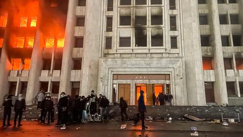 Protestierende stehen vor dem brennenden Rathaus von Almaty in Kasachstan. 