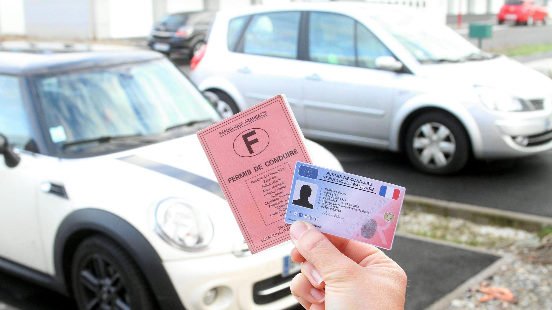 Eine Hand hält einen europäischen und einen französischen Führerschein.