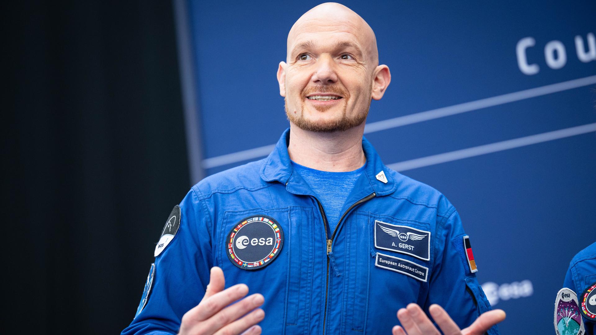 Astronaut Alexander Gerst im blauen Overall gestikuliert lächelnd bei der Esa-Ministerratstagung. Astronaut Alexander Gerst im blauen Overall gestikuliert lächelnd bei der Esa-Ministerratstagung.