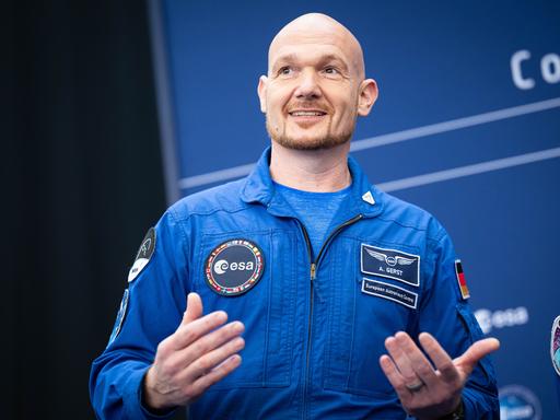 Astronaut Alexander Gerst im blauen Overall gestikuliert lächelnd bei der Esa-Ministerratstagung. Astronaut Alexander Gerst im blauen Overall gestikuliert lächelnd bei der Esa-Ministerratstagung.