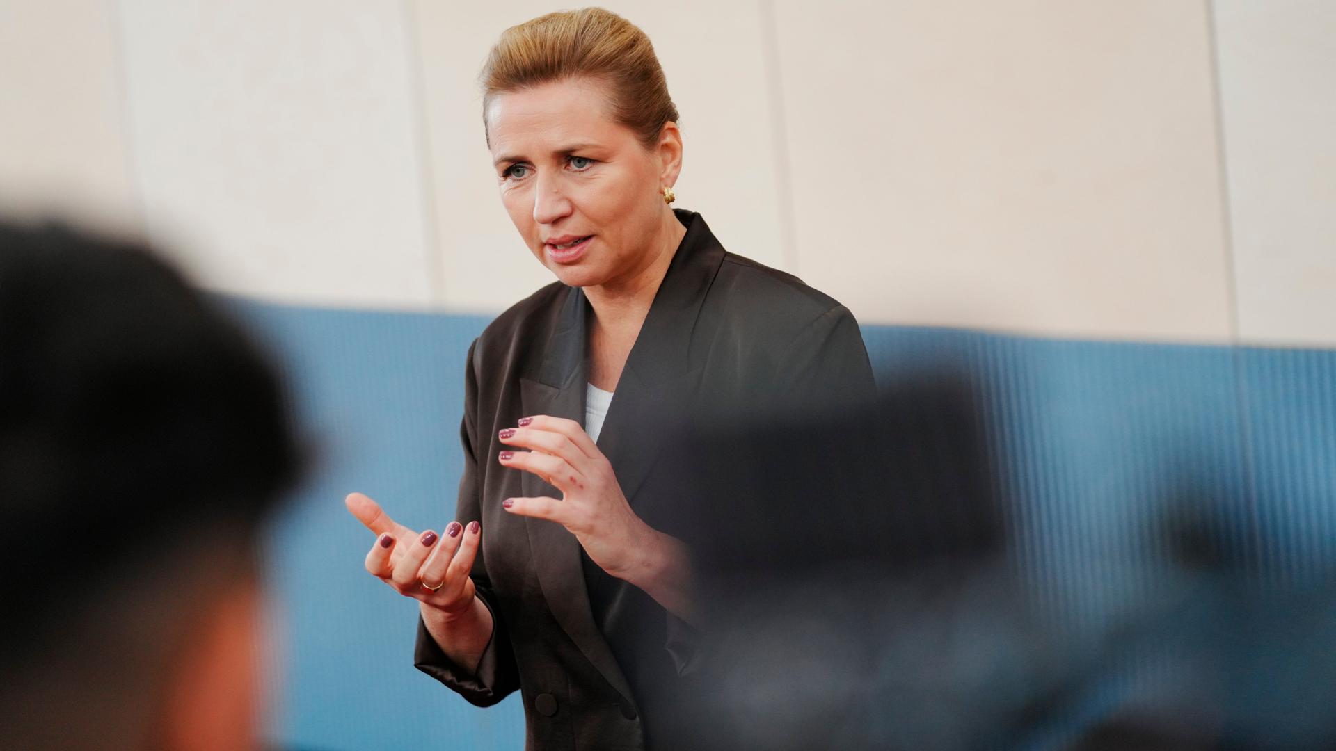 Dänemarks Regierungschefin Frederiksen steht vor Journalisten und gestikuliert mit beiden Händen.