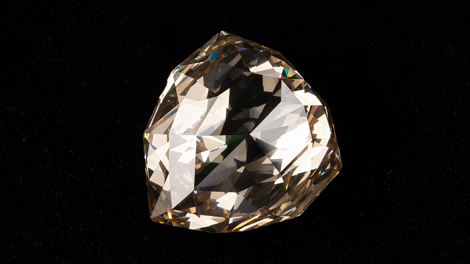 Ein riesiger, bräunlich schimmernder Diamant vor schwarzem Hintergrund. Ein riesiger, bräunlich schimmernder Diamant vor schwarzem Hintergrund.