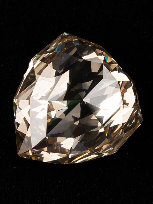 Ein riesiger, bräunlich schimmernder Diamant vor schwarzem Hintergrund. Ein riesiger, bräunlich schimmernder Diamant vor schwarzem Hintergrund.