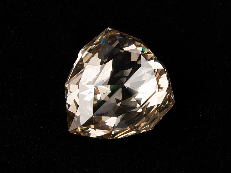 Ein riesiger, bräunlich schimmernder Diamant vor schwarzem Hintergrund. Ein riesiger, bräunlich schimmernder Diamant vor schwarzem Hintergrund.