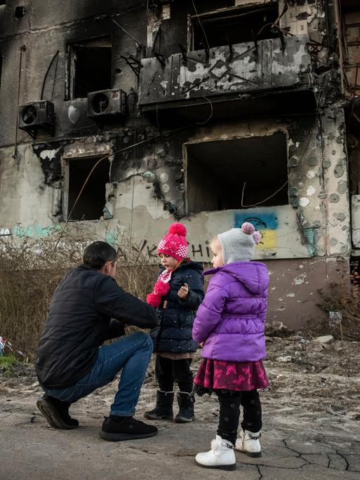 Mann und Kinder in einem zerstörten Haus in Borodyanska in der Region Kiew in der Ukraine