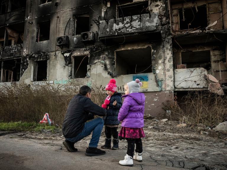 Mann und Kinder in einem zerstörten Haus in Borodyanska in der Region Kiew in der Ukraine Mann und Kinder in einem zerstörten Haus in Borodyanska in der Region Kiew in der Ukraine