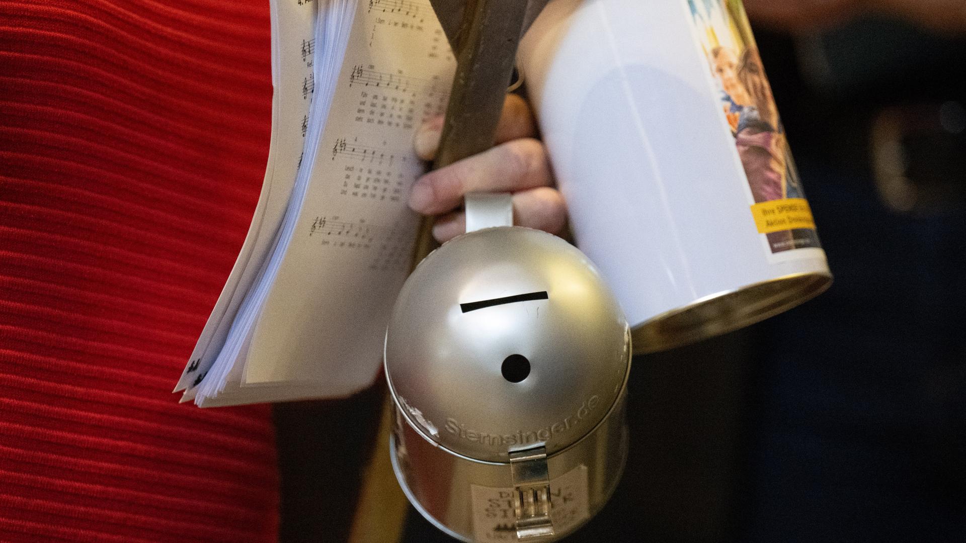 Eine Frau hält Spendendosen in der Hand. Eine Frau hält Spendendosen in der Hand.