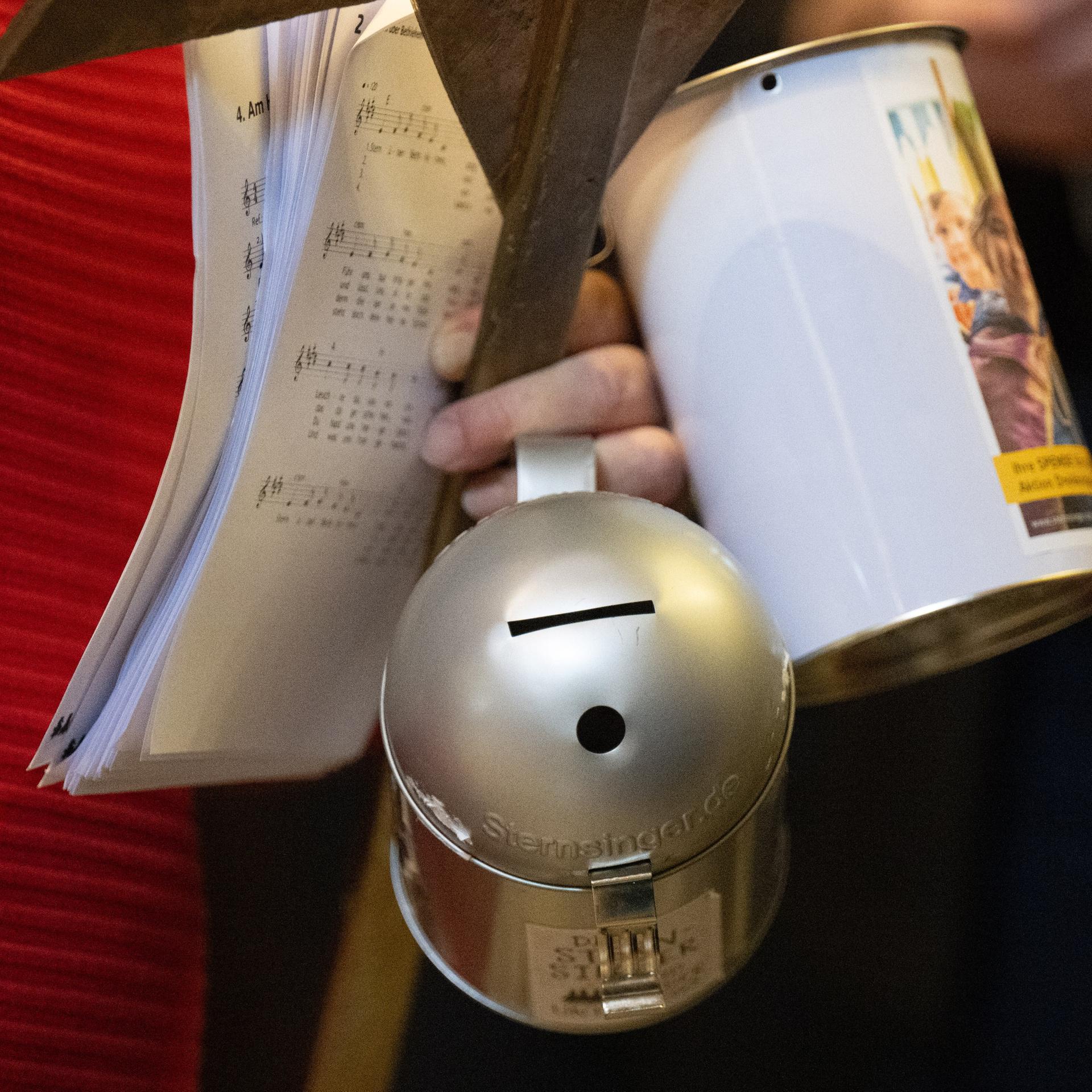 Eine Frau hält Spendendosen in der Hand.