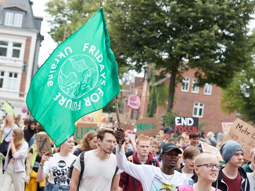 Ein Teilnehmer eines Protestzugs der Klimabewegung Fridays for Future trägt eine Fahne mit der Aufschrift "Fridays for Future".