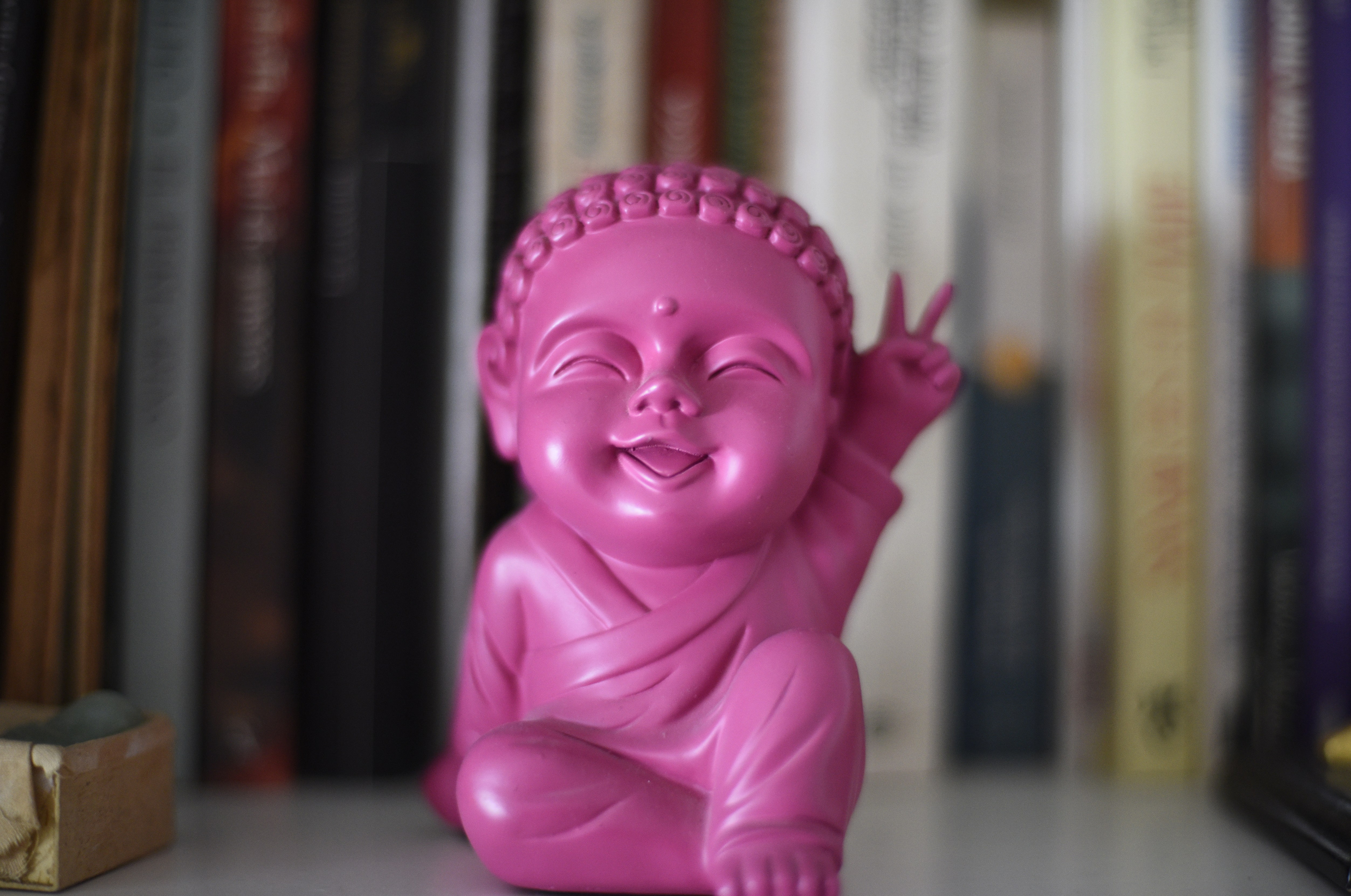 Close-Up auf eine pinke Buddha-Palstikfigur.