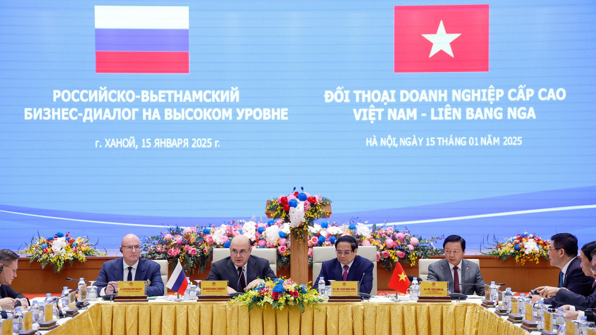 Der russische Ministerpräsident Michail Mischustin bei einem Treffen in Hanoi; er sitzt mit mehreren anderen Personen der russischen und vietnamesischen Delegation an einem U-förmigen Tisch. 