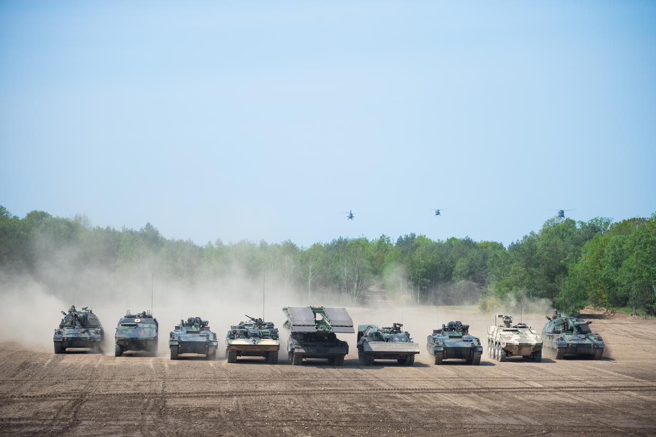 Mehrere Panzer der schnellen Eingreiftruppe der NATO fahren während einer Vorführung in einer Reihe über ein leeres Feld. 