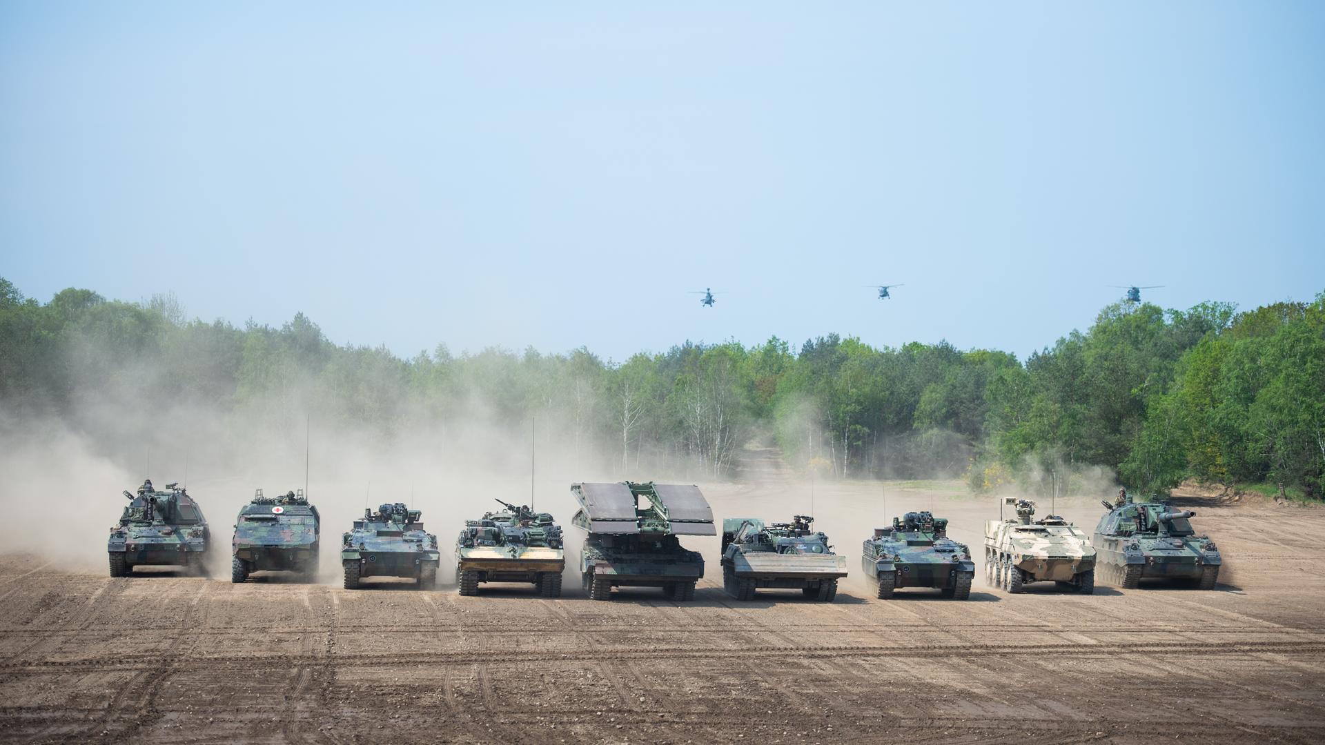 Mehrere Panzer der schnellen Eingreiftruppe der NATO fahren während einer Vorführung in einer Reihe über ein leeres Feld. Mehrere Panzer der schnellen Eingreiftruppe der NATO fahren während einer Vorführung in einer Reihe über ein leeres Feld.