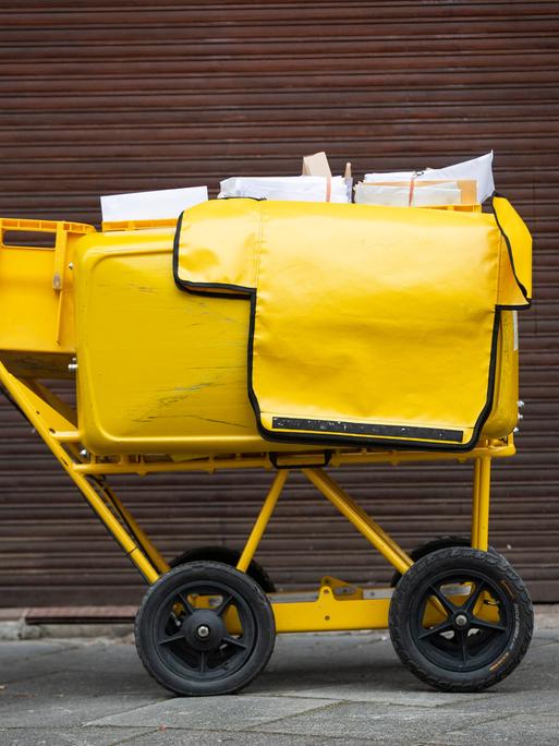 Ein Briefträgerwagen der Deutschen Post für die Hausbelieferung steht auf einer Straße.