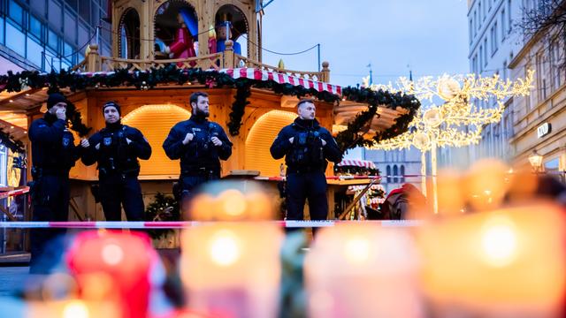 Polizisten sichern den Weihnachtsmarkt, wobei Kerzen vor ihnen brennen.