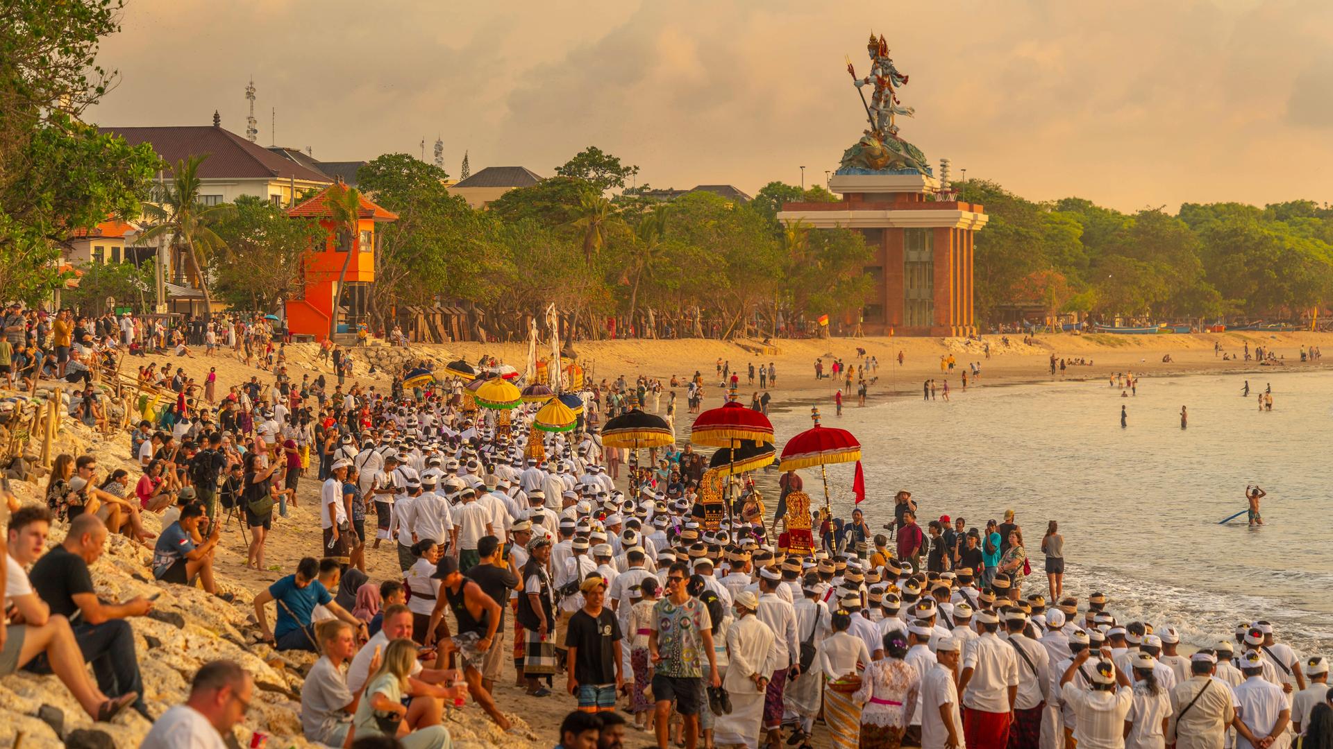 Blick auf den Strand in Kuta. Zu sehen sind sowohl Touristen als auch Balinesen in traditioneller Kleidung