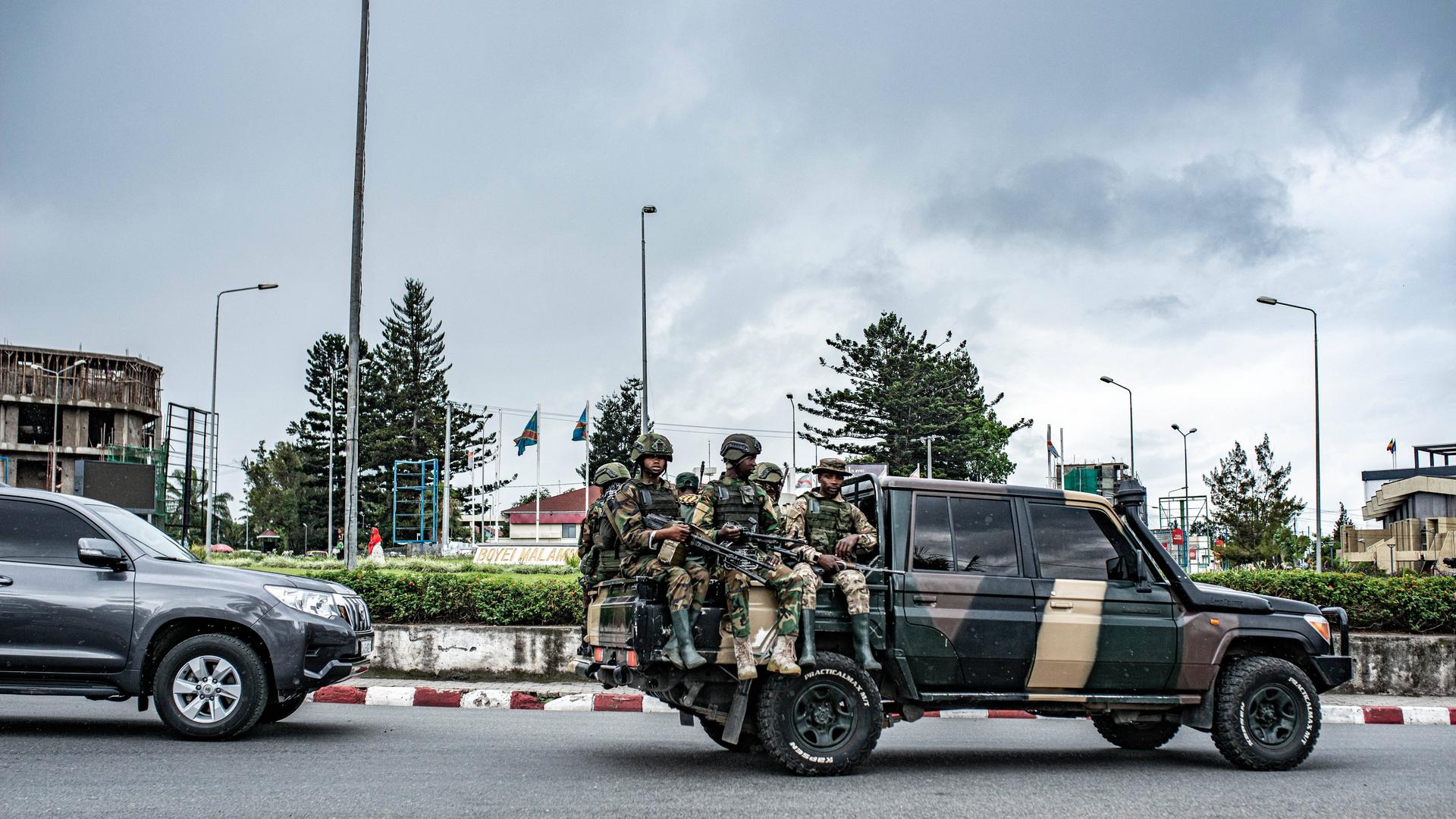 Soldaten der Miliz M23 sitzen auf der Ladefläche eines Pick-ups. Sie tragen Uniformen und Waffen.