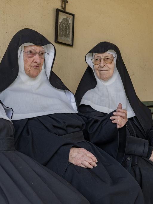 Drei alte Frauen in Ordensornat (Schwester Rita, Schwester Bernadette, Schwester Regina sitzen nebeneinander auf einer Bank Drei alte Frauen in Ordensornat (Schwester Rita, Schwester Bernadette, Schwester Regina sitzen nebeneinander auf einer Bank