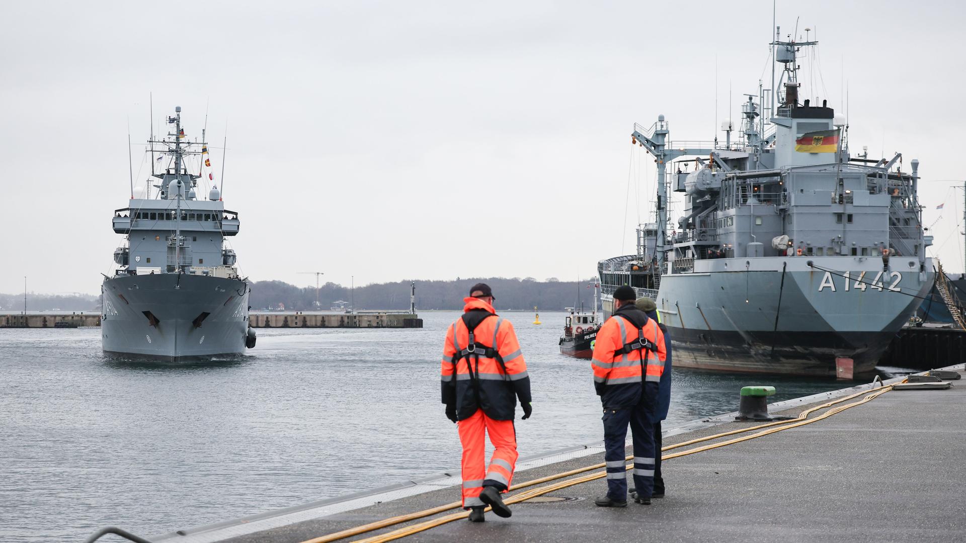 Das Versorgungsschiff "Werra" und das Minenjagdboot "Weilheim" im Hafen des Marinestützpunktes Kiel. Am Kai stehen zwei Arbeiter.