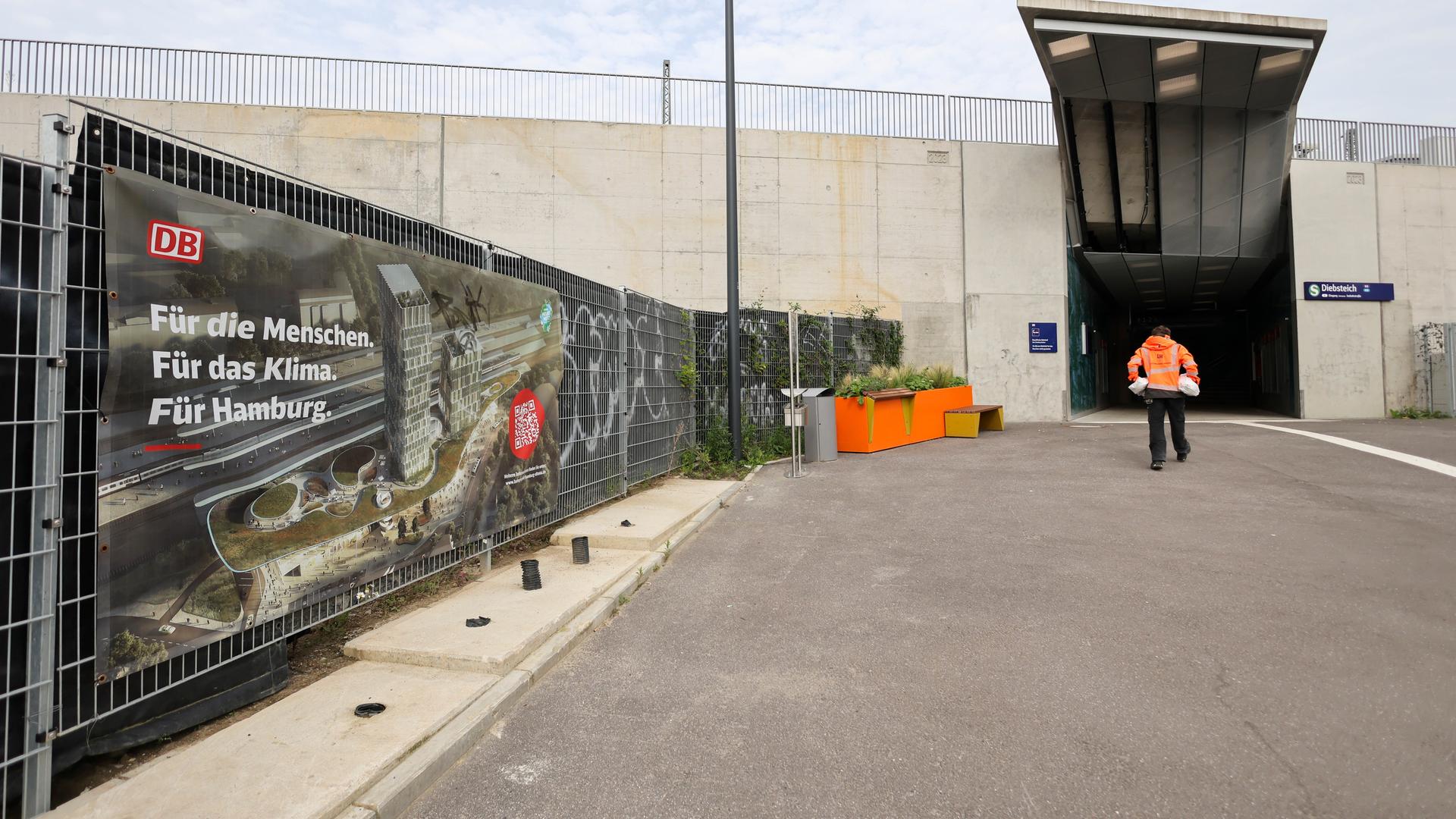 Hamburg: Ein Werbeplakat der Deutschen Bahn mit der Animation eines neuen Bahnhofs ist an einem Zaun neben dem Zugang zur umgebauten S-Bahnstation Diebsteich zu sehen. Hamburg: Ein Werbeplakat der Deutschen Bahn mit der Animation eines neuen Bahnhofs ist an einem Zaun neben dem Zugang zur umgebauten S-Bahnstation Diebsteich zu sehen.