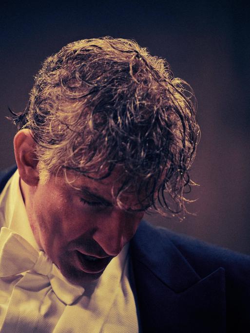Bradley Cooper in der Rolle als Leonard Bernstein senkt sein verschwitztes Haupt nach einem Film-Dirigat in Konzertkleidung.