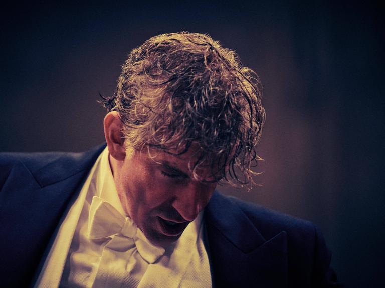 Bradley Cooper in der Rolle als Leonard Bernstein senkt sein verschwitztes Haupt nach einem Film-Dirigat in Konzertkleidung.
