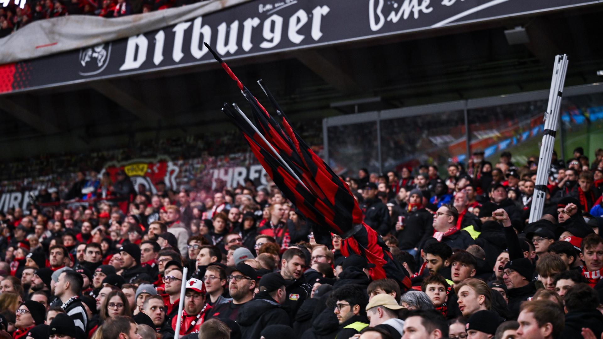 Man sieht mehrere eingerollte schwarz-rote Fahnen auf der noch vollbesetzten Tribüne. Auf dem Gang gehen viele Fans aber bereits nach oben zum Ausgang. Man sieht mehrere eingerollte schwarz-rote Fahnen auf der noch vollbesetzten Tribüne. Auf dem Gang gehen viele Fans aber bereits nach oben zum Ausgang.