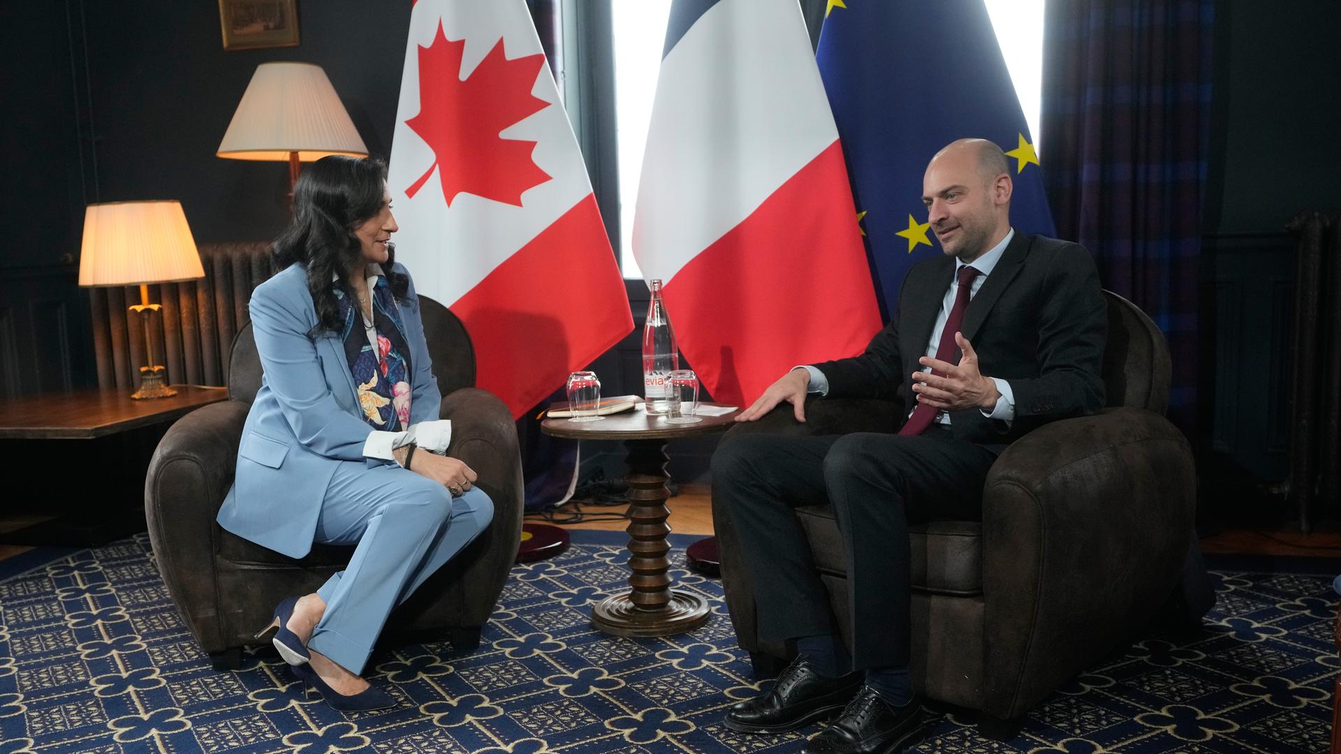 Die kanadische Außenministerin Anand trifft ihren französichen Kollegen Barrot sitzen in Sesseln nebeneinander, hinter ihnen die Landesfahnen. Die kanadische Außenministerin Anand trifft ihren französichen Kollegen Barrot sitzen in Sesseln nebeneinander, hinter ihnen die Landesfahnen.