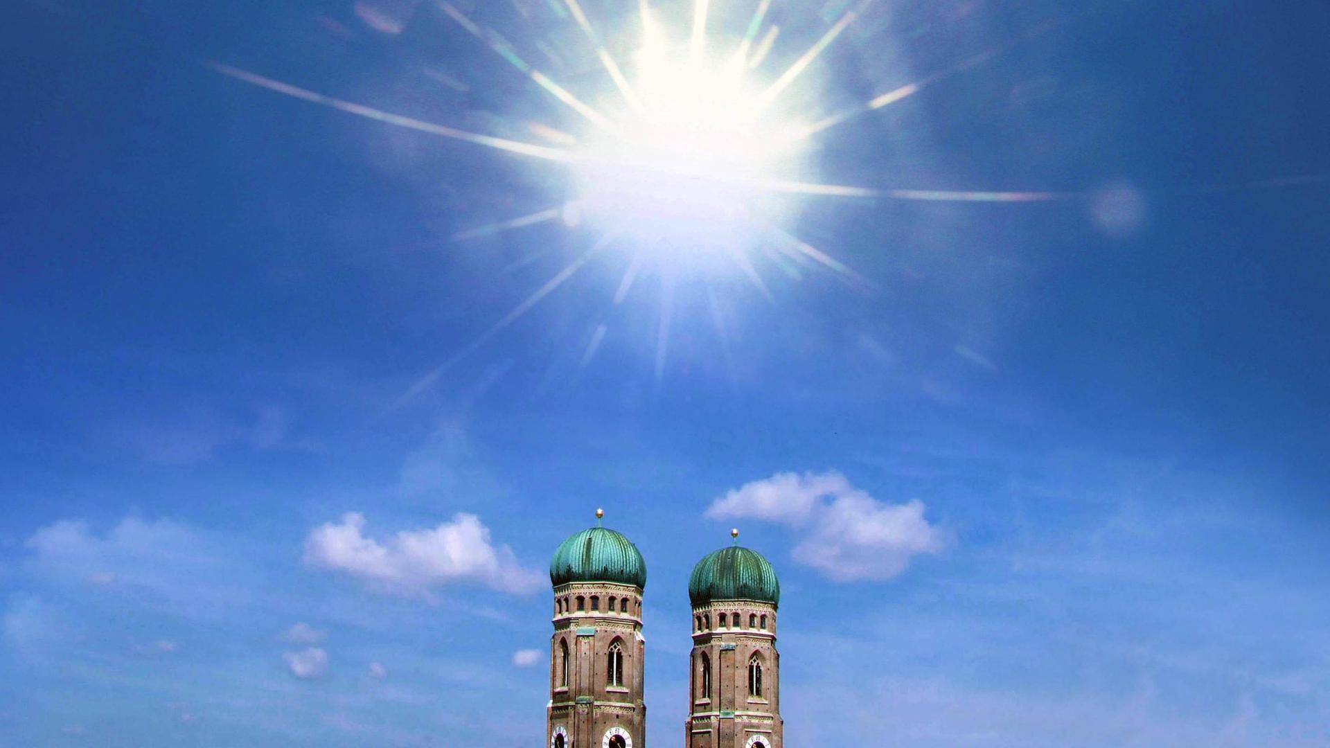 Die Türme der Frauenkirche in München vor blauem Himmel und viel Sonnenschein. Es wirkt sehr heiß. Die Türme der Frauenkirche in München vor blauem Himmel und viel Sonnenschein. Es wirkt sehr heiß.