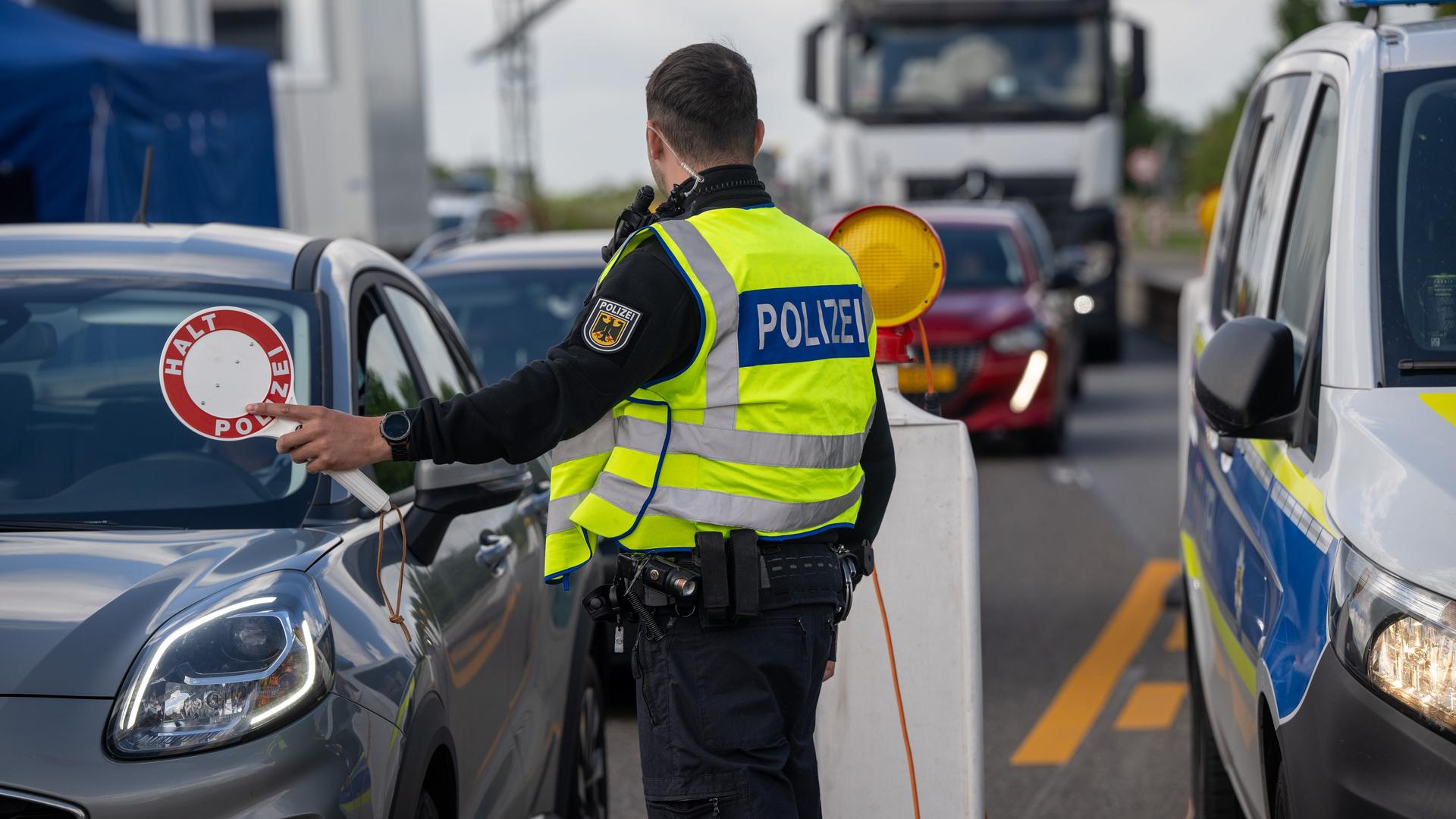 Ein Bundespolizist stoppt auf der Autobahn 64 ein Fahrzeug.