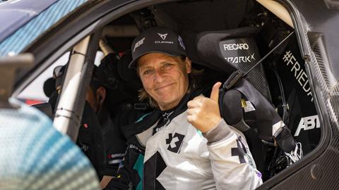 Jutta Kleinschmidt. Eine Fraut sitzt in einem Rennwagen.
