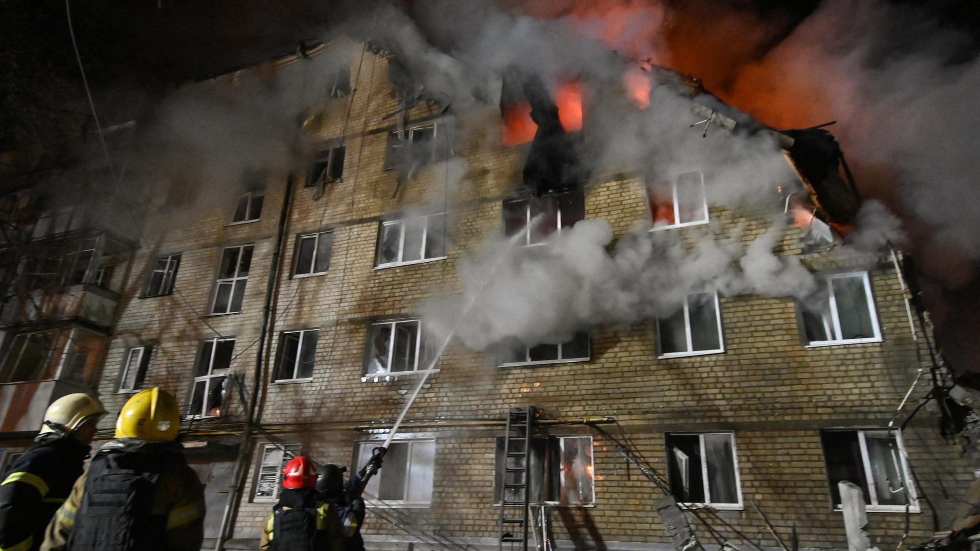 Feuerwehrleute löschen einen Brand und räumen Trümmer in einem Wohngebäude in der Stadt Charkiw.
