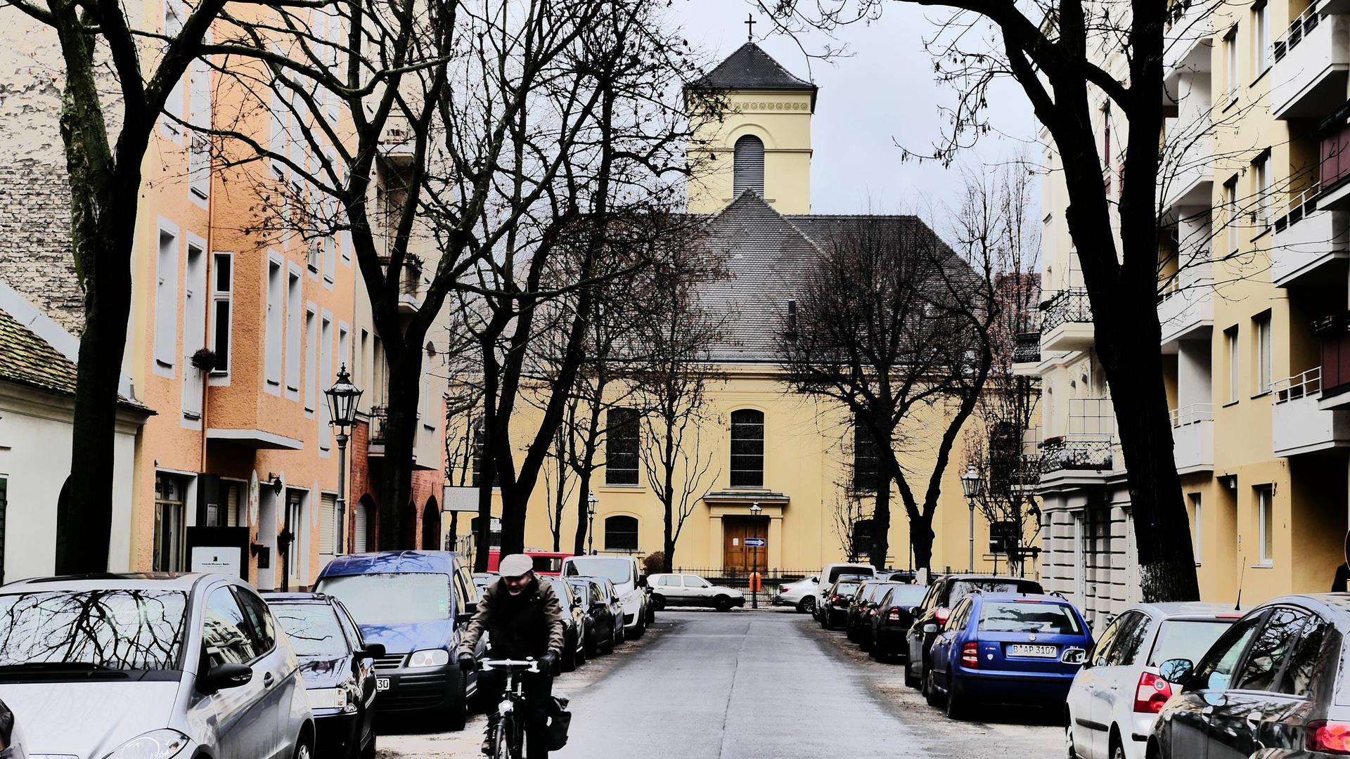 Aufnahme der winterlichen Luisenkirche in Berlin. Auf der Straße davor stehen Autos. Ein Rafahrer fährt in Richtung der Kamera. Aufnahme der winterlichen Luisenkirche in Berlin. Auf der Straße davor stehen Autos. Ein Rafahrer fährt in Richtung der Kamera.
