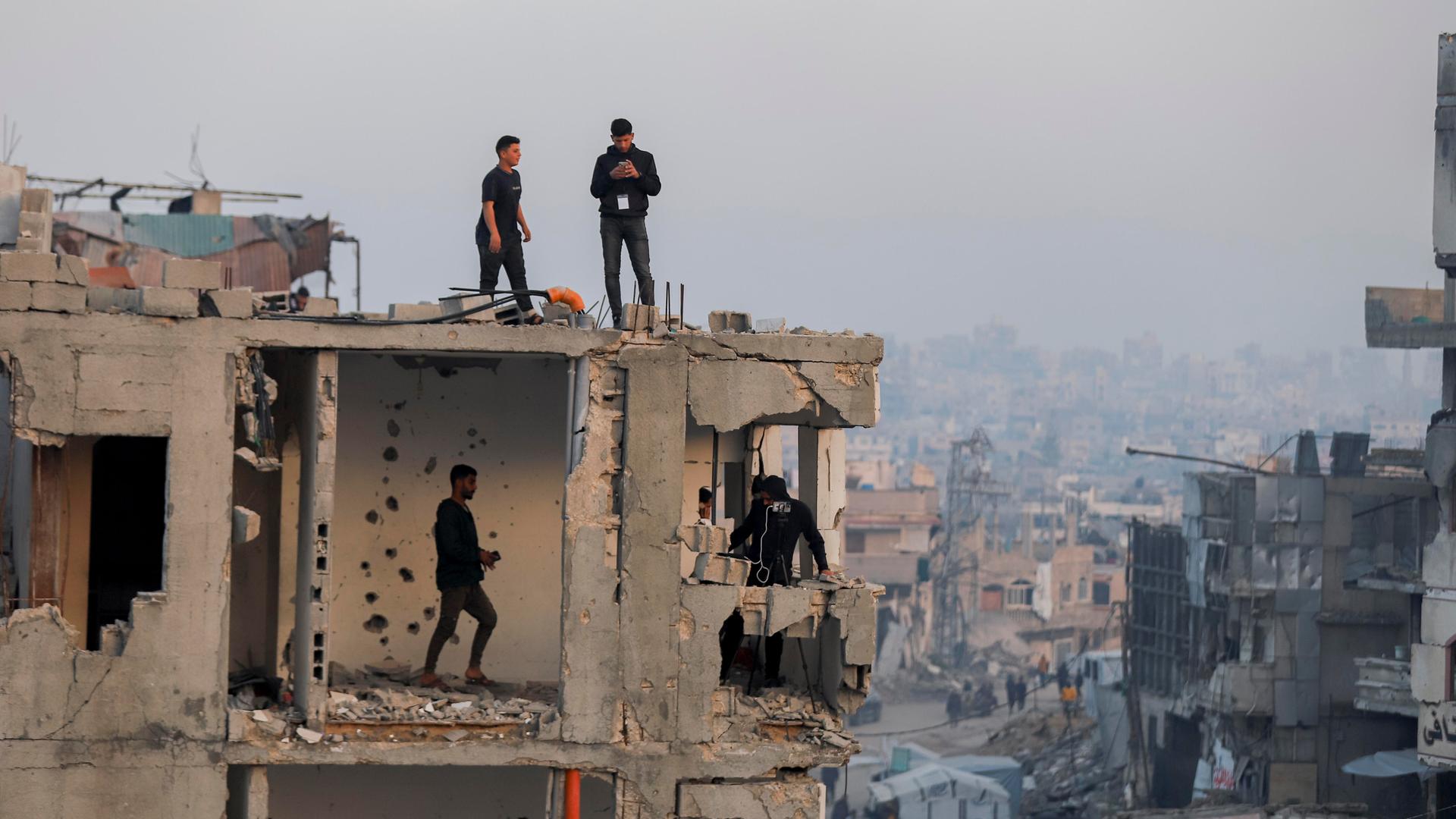 Eine Gruppe von Männern steht auf einem zerstörten Haus inmitten einer Trümmerlandschaft in Beit Lahia im Norden des Gazastreifens. 