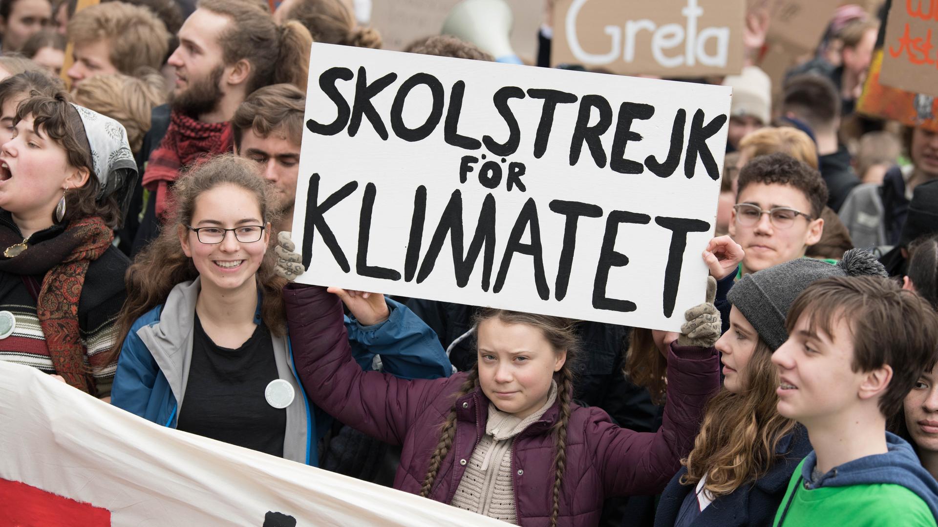 Mehrere junge Menschen stehen zusammen und halten Plakate hoch, sie demonstrieren für Klimaschutz.