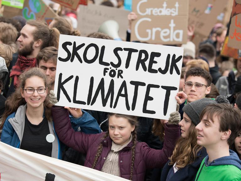 Mehrere junge Menschen stehen zusammen und halten Plakate hoch, sie demonstrieren für Klimaschutz.