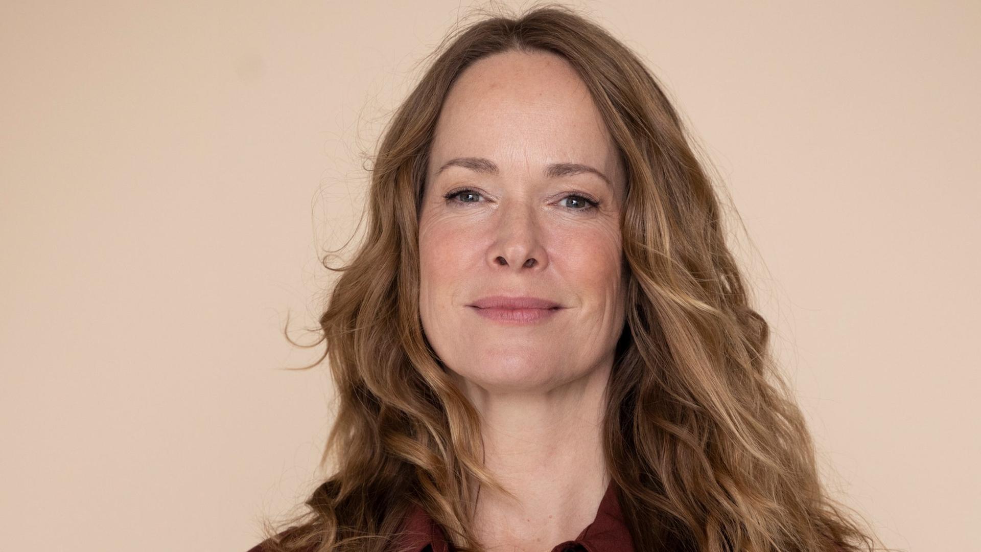 Sophie Rosengtreter steht vor einem hellen Hintergrund und hält Publikationen zum Thema Demenz in der Hand.