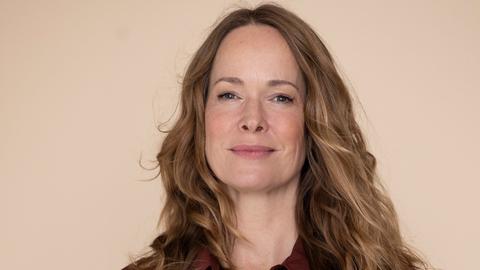 Sophie Rosengtreter steht vor einem hellen Hintergrund und hält Publikationen zum Thema Demenz in der Hand.