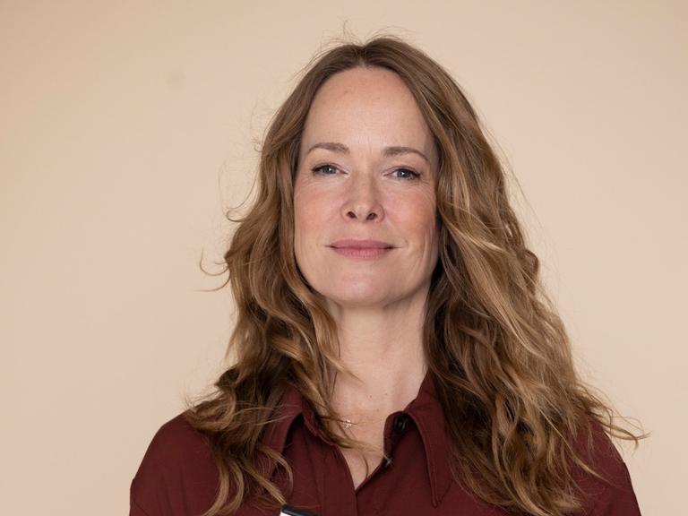 Sophie Rosengtreter steht vor einem hellen Hintergrund und hält Publikationen zum Thema Demenz in der Hand.