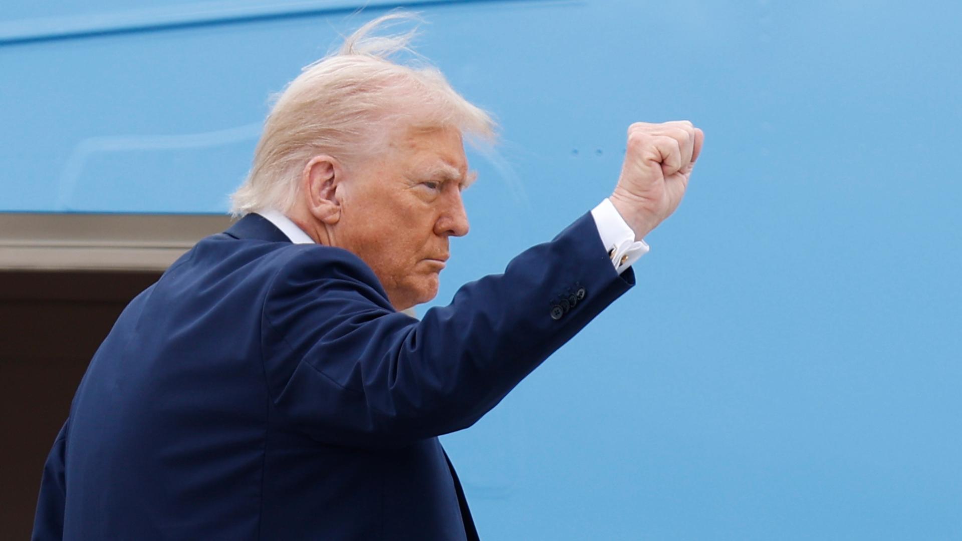 Trump im dunklen Jackett ballt die Faust. Man sieht ihn von der Seite. Trump im dunklen Jackett ballt die Faust. Man sieht ihn von der Seite.