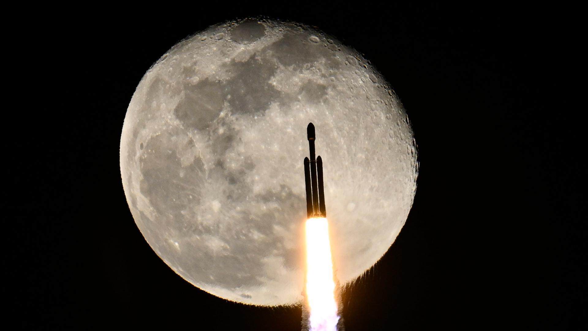 SpaceX-Rakete nach dem Start, im Hintergrund ist der Mond zu sehen.